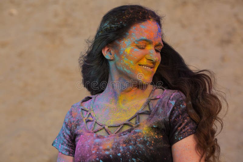 Closeup portrait of joyful brunette model posing covered with dry Holi paint at the desert. Closeup portrait of joyful brunette girl posing covered with dry Holi royalty free stock photography